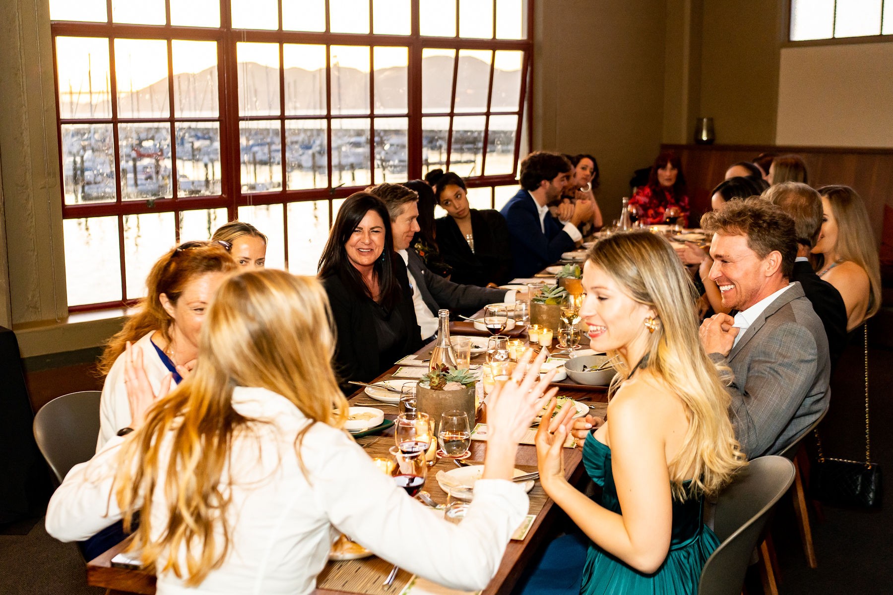 Guests laughing over a toast, the marina in the window behind them