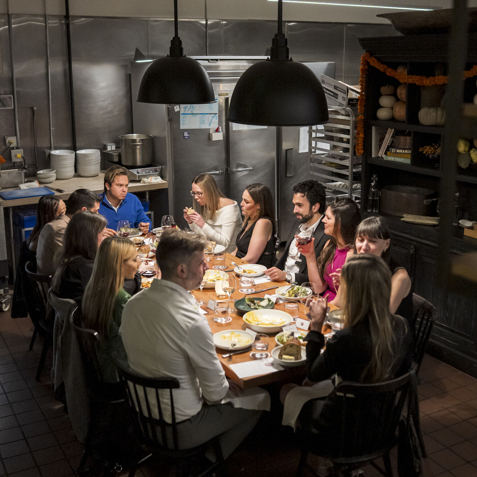 A full table in the back-of-house kitchen, guests turned toward each other